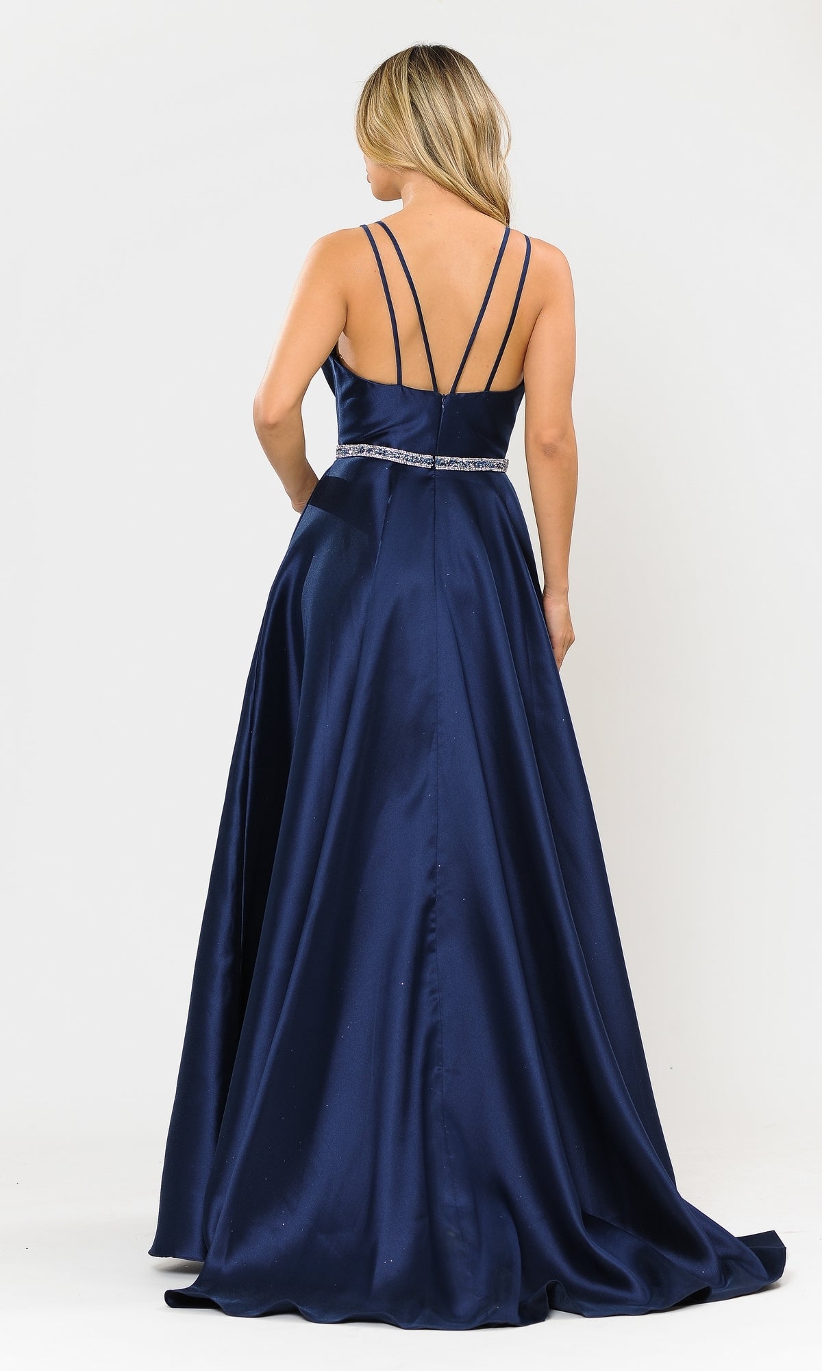 A woman faces away in the Long A-Line Mikado Prom Gown 8690 with pockets, featuring thin crisscross straps and a fitted waist, in navy blue, displayed against a plain white background.